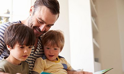 Vater liest zusammen mit seinen zwei Kindern