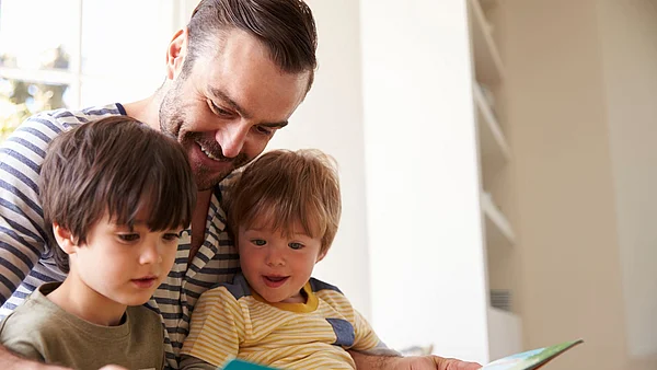 Vater liest zusammen mit seinen zwei Kindern