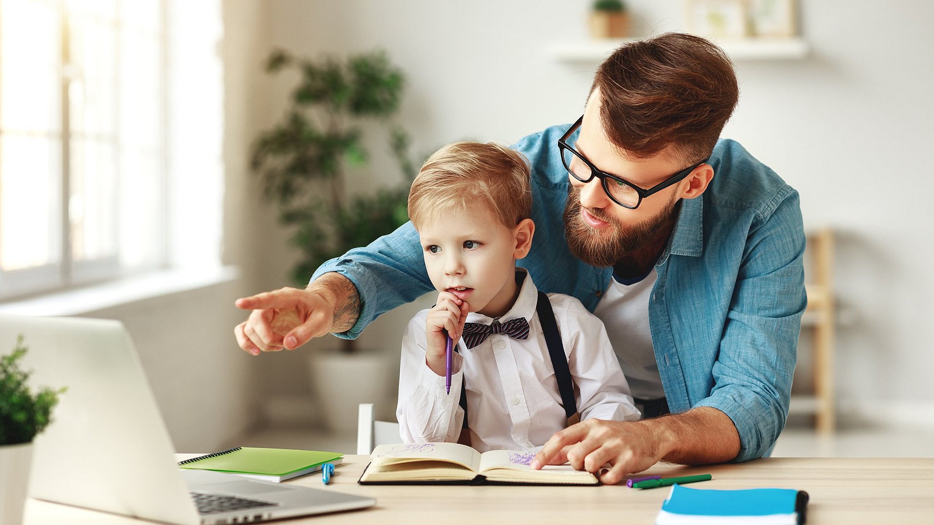 Vater hilft seinem Sohn beim Online-Unterricht am Laptop