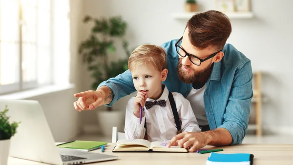 Vater hilft seinem Sohn beim Online-Unterricht am Laptop