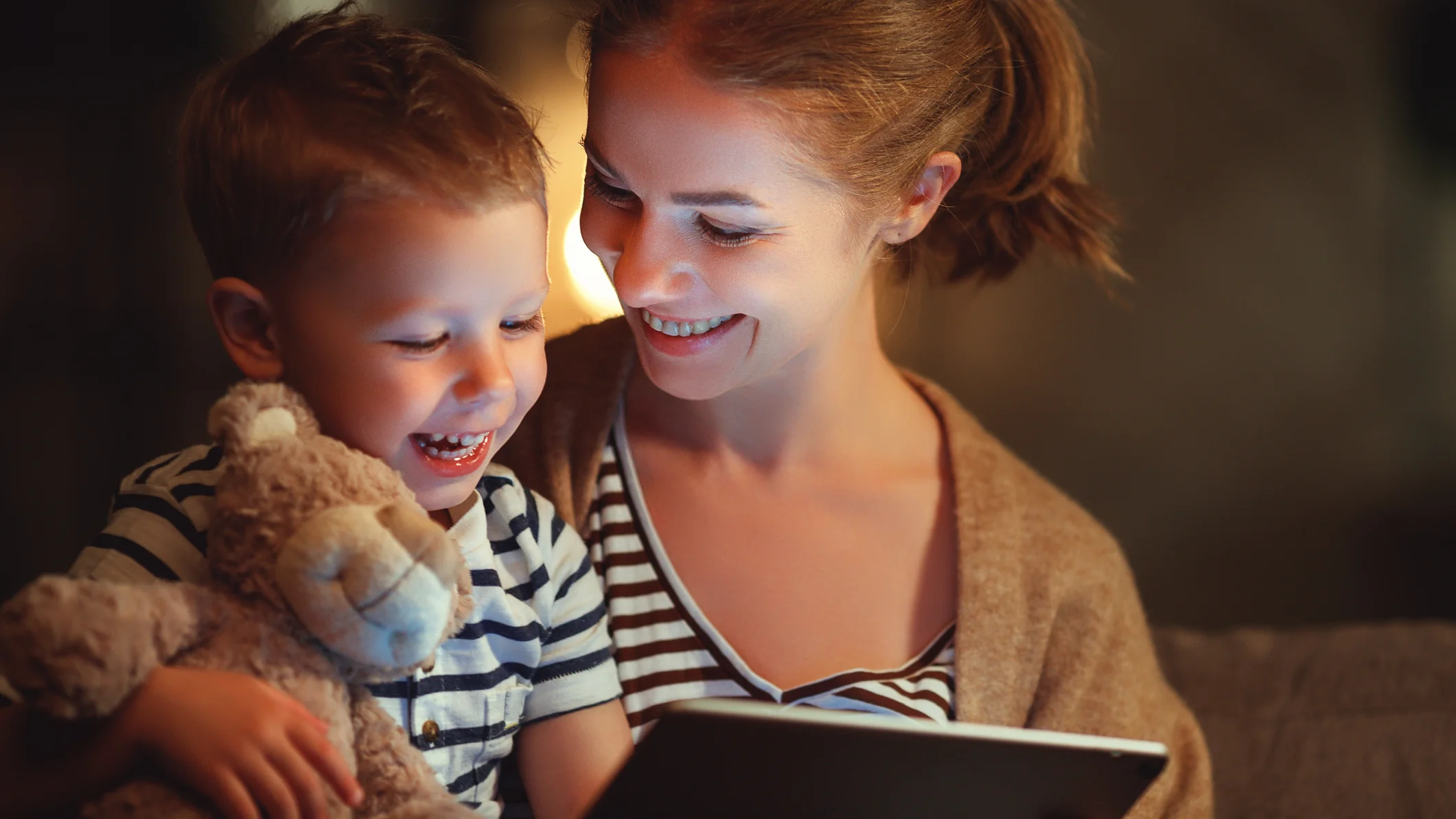 Mutter und Sohn lachen während sie etwas auf dem Tablett schauen 