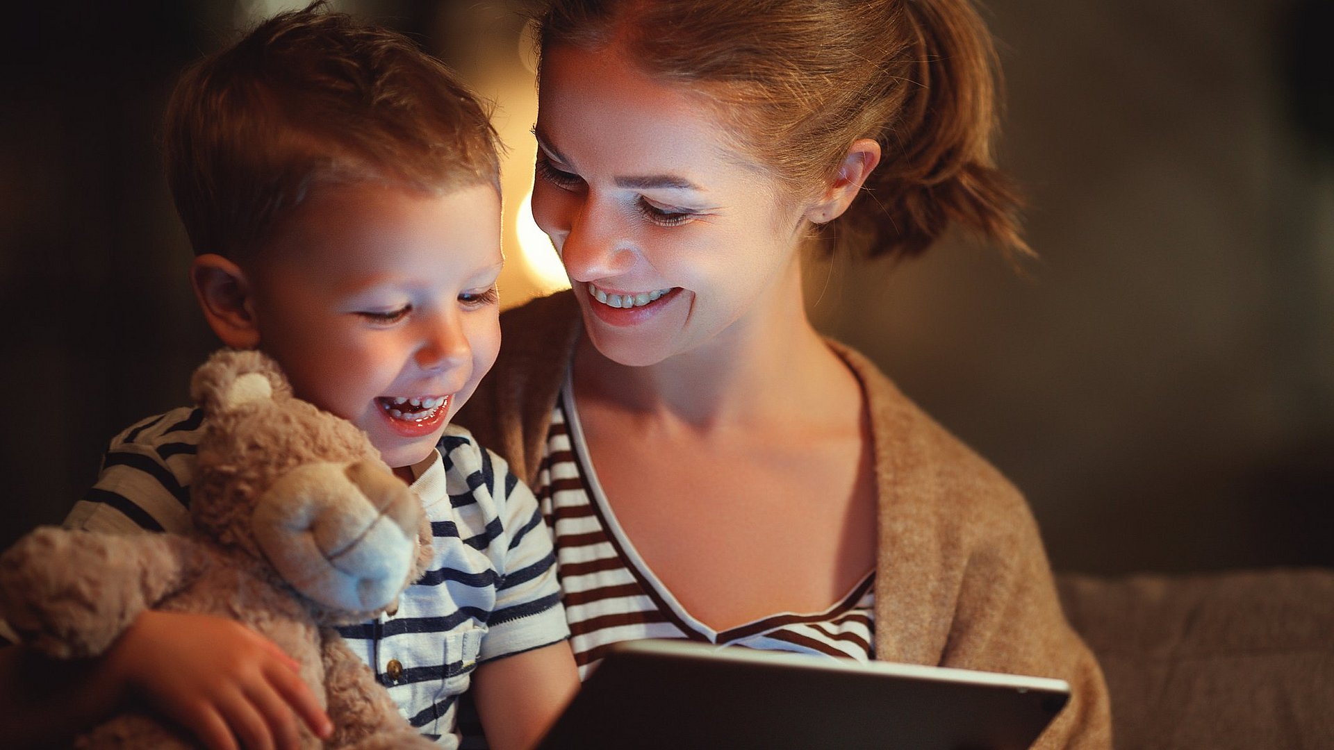 Mutter und Sohn lachen während sie etwas auf dem Tablett schauen 