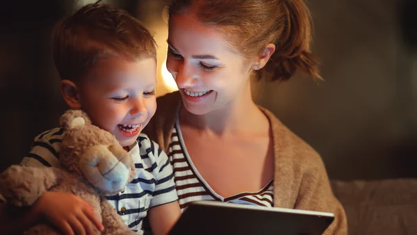 Mutter und Sohn lachen während sie etwas auf dem Tablett schauen 