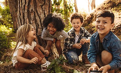 Vier Kinder lachen gemeinsam im Wald