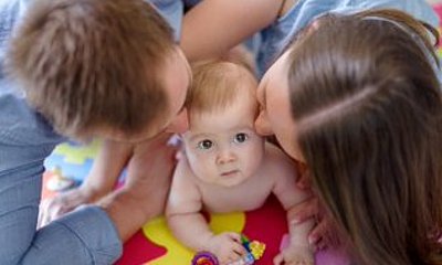 Mutter und Vater geben ihrem Kind einen Kuss auf die Backen