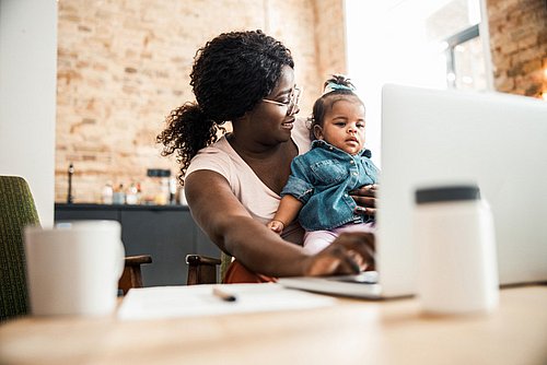 Mutter_arbeitet_am_Laptop_und_hat_Baby_im_Schoss