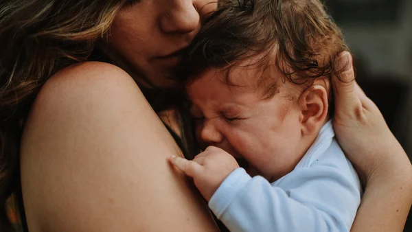 Baby weint in den Armen seiner Mutter