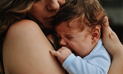 Baby weint in den Armen seiner Mutter