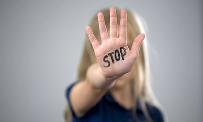 MÄdchen hält ihre offene Hand in die Kamera. Auf der Hand steht groß &quot;STOPP&quot; geschrieben. 