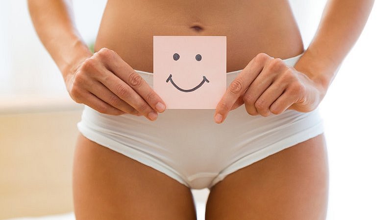 Eine Frau hält einen Post-IT Zettel mit einem Smiley for den Bauch