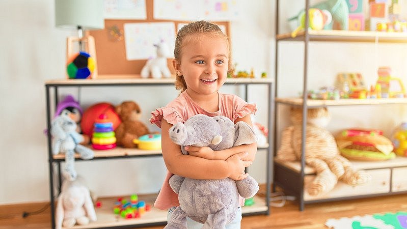 Mädchen im Kindergarten hält Stofftier in den Armen