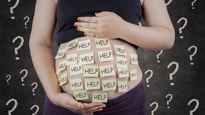 Babybauch mit Zetteln mit der Aufschrift Help