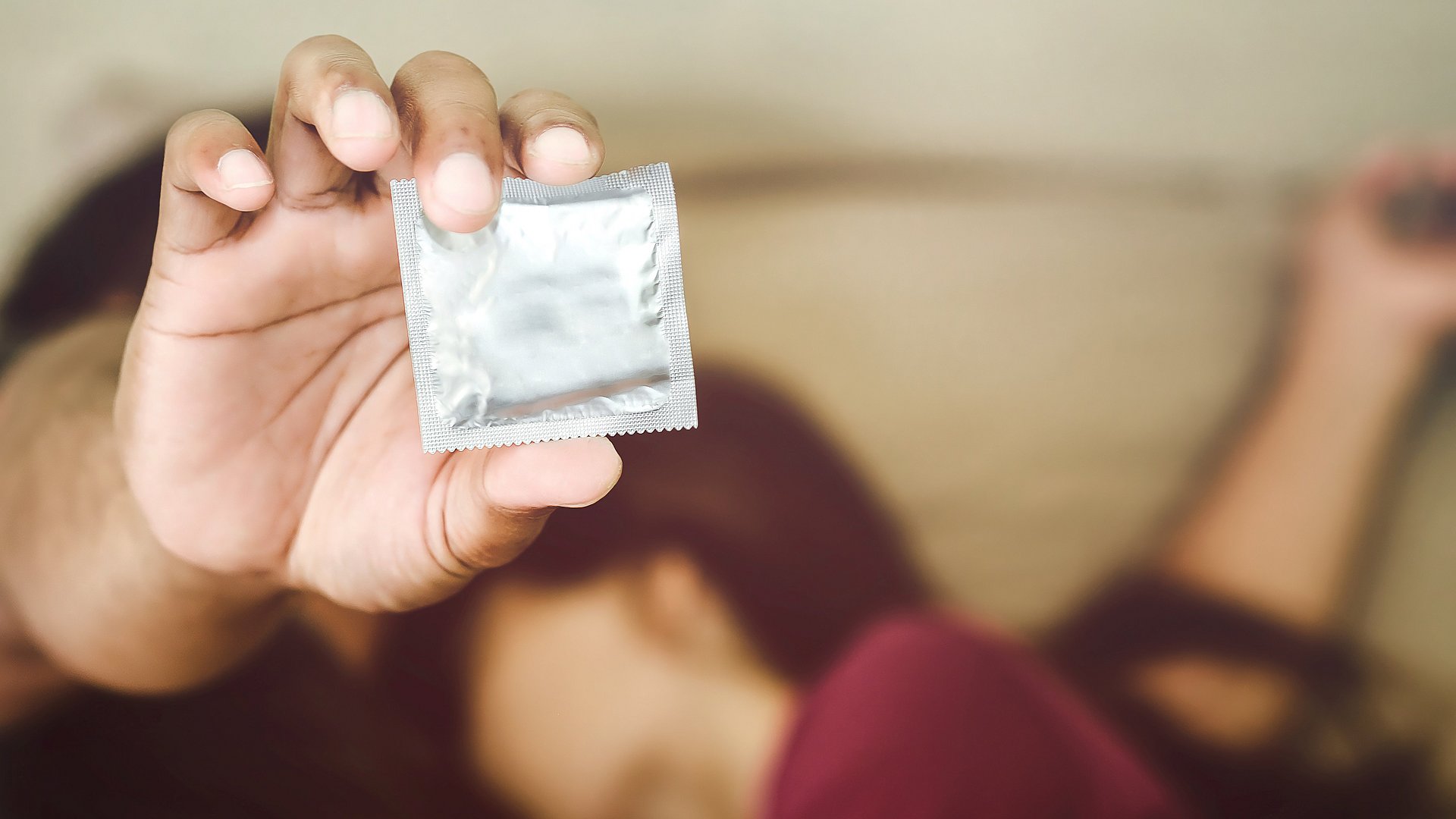 Hand hält ein verpacktes Kondom
