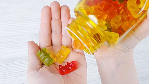 Hand hat Gummibärchen aus einem Glas