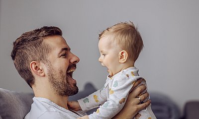 Vater und kleiner Junge lachen sich an