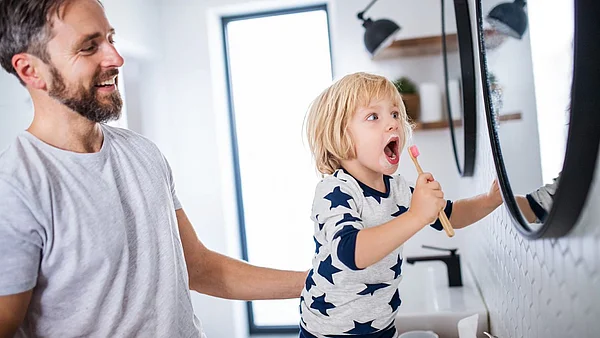 Vater guckt seinem Sohn beim Zähneputzen zu