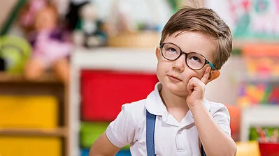 kleiner Junge mit Brille schaut nachdenklich