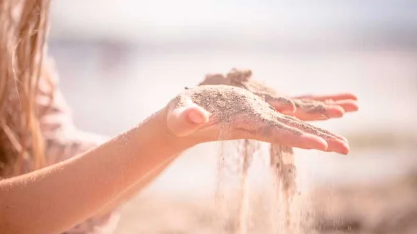 Kind_laesst_sand_durch_haende_rieseln.jpg