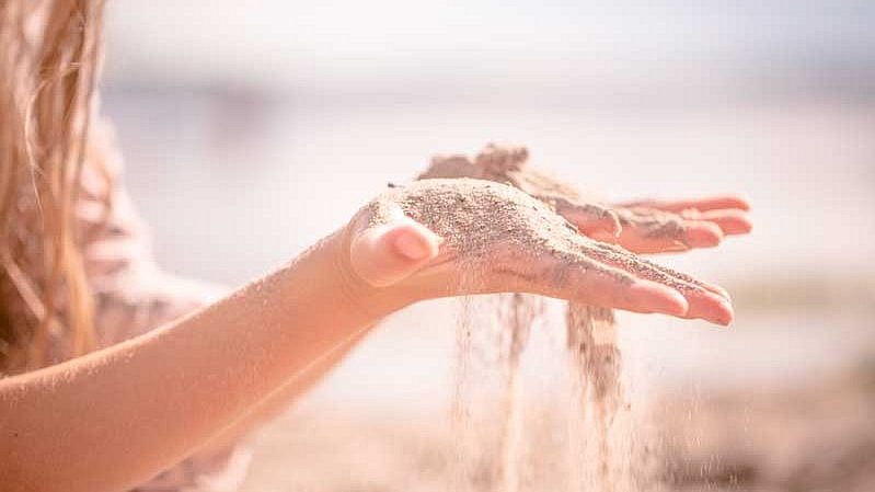 Kind_laesst_sand_durch_haende_rieseln.jpg