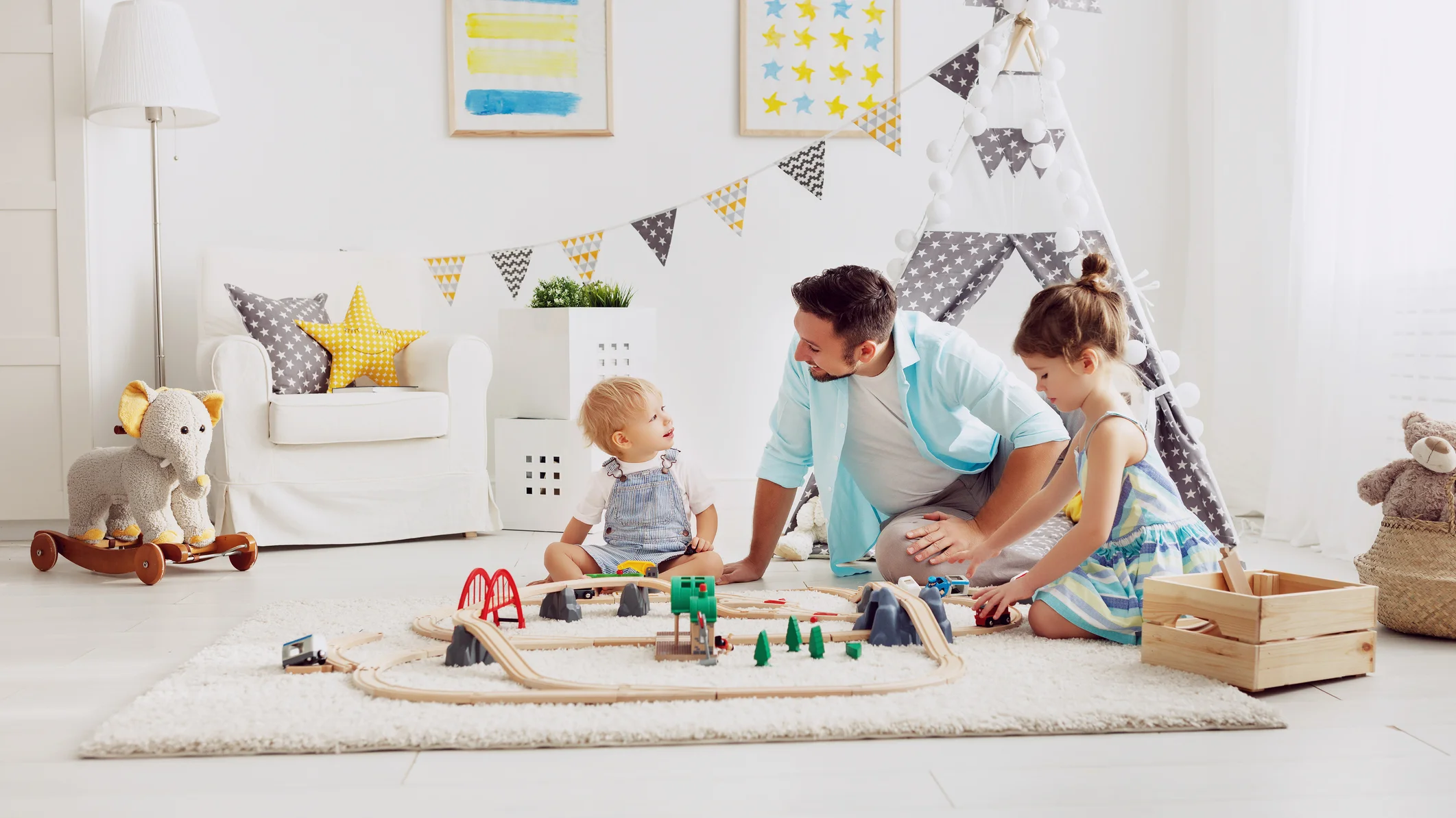 Familien Vater und seine Kinder spielen mit einer Spielzeug -Eisenbahn im Spielzimmer