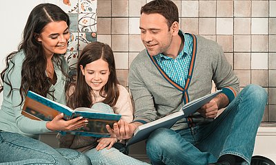 Vater und Mutter lesen mit ihrer Tochter