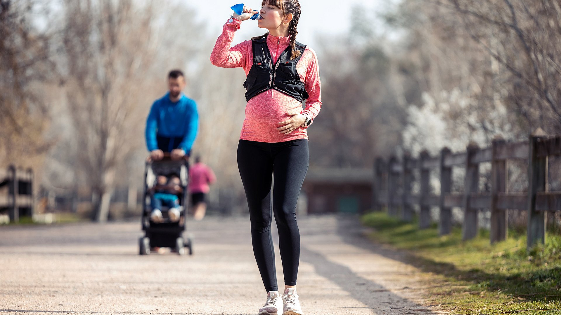 Schwangere Frau ist Joggen und Trinkt Wasser