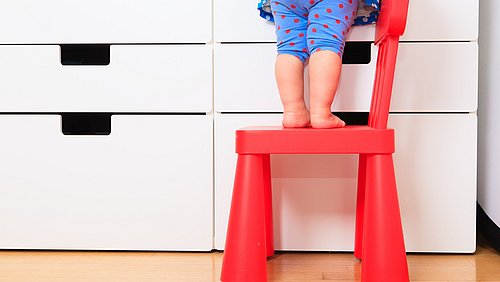 Kleines Kind klettert auf einem Stuhl