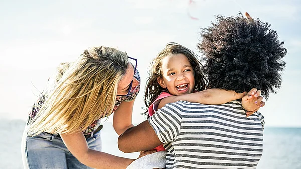 Vater und Mutter haben Spaß mit ihrer Tochter und umarmen sie.