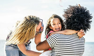 Vater und Mutter haben Spaß mit ihrer Tochter und umarmen sie.