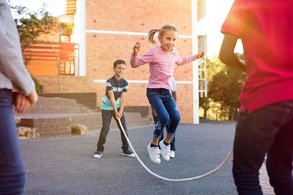 Kinder spielen Springseilspringen draussen auf einem Hof