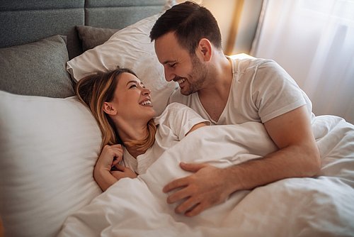 Pärchen liegt im Bett und lächelt