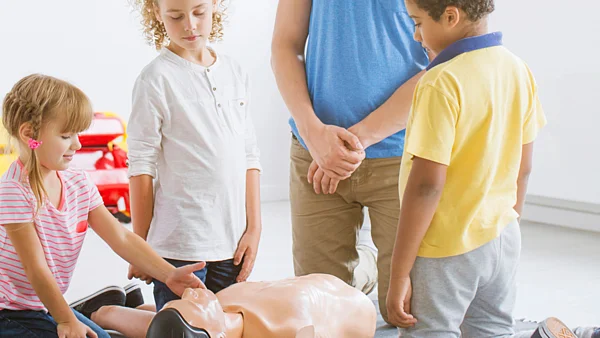 Kinder übern Wiederbelebung an einer Puppe