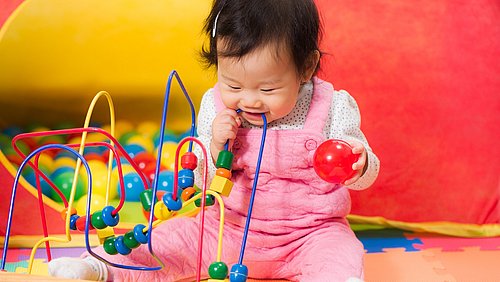 Kleines Mädchen spielt mit Spielzeug und Bällen