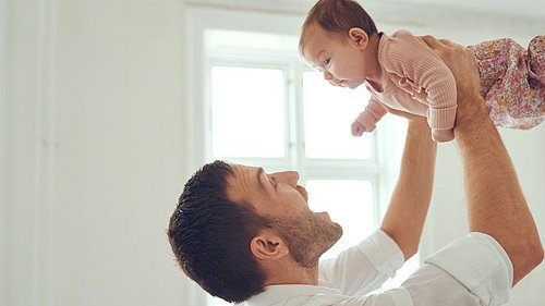 Ein Mann hält ein Baby in die Luft