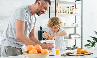 Vater hilft Sohn beim Orangen pressen