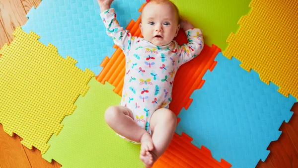 Baby liegt auf bunten Matten