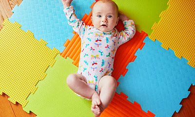 Baby liegt auf bunten Matten