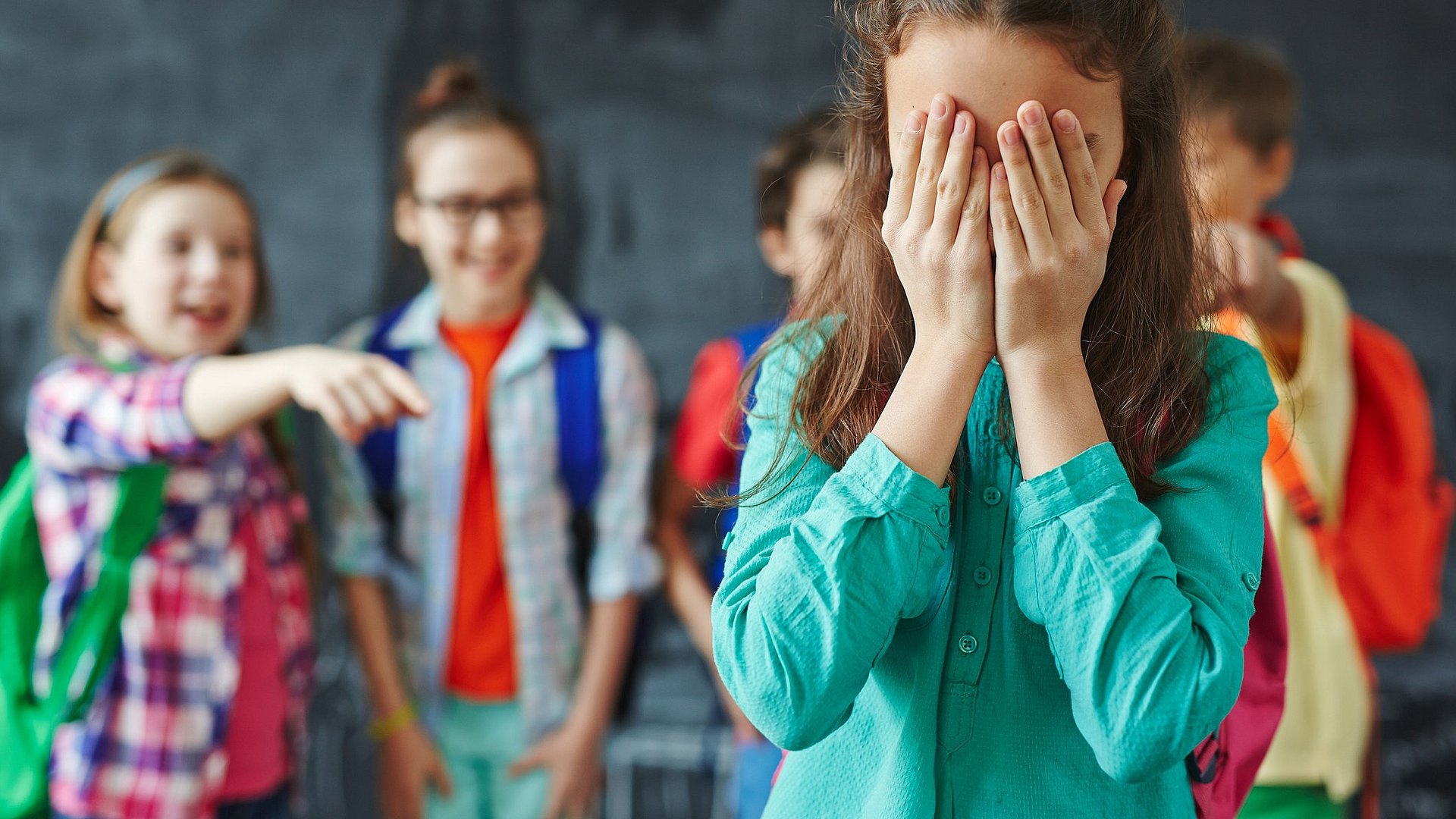 Kinder lachen ein weinendes Mädchen aus