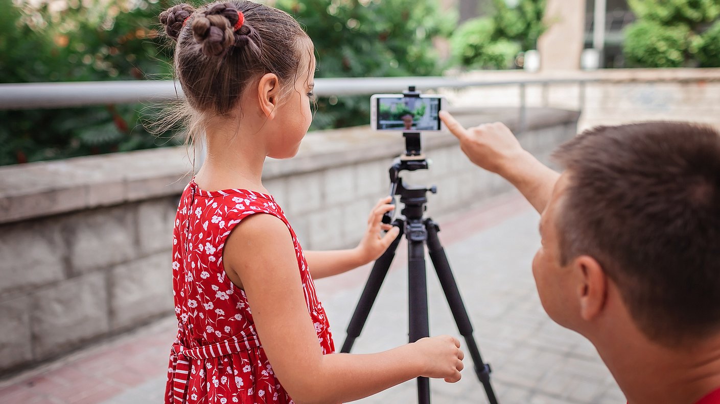 Vater und Tochter drehen zusammen ein Video auf dem Handy