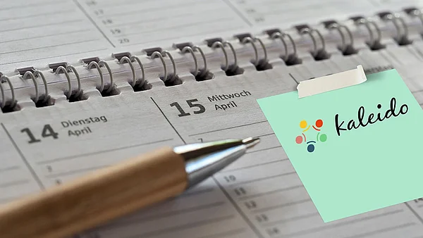 Ein Kalender im Ringblockformat mit einem Notizzetel wo das Logo und der Name: Kaleido steht.