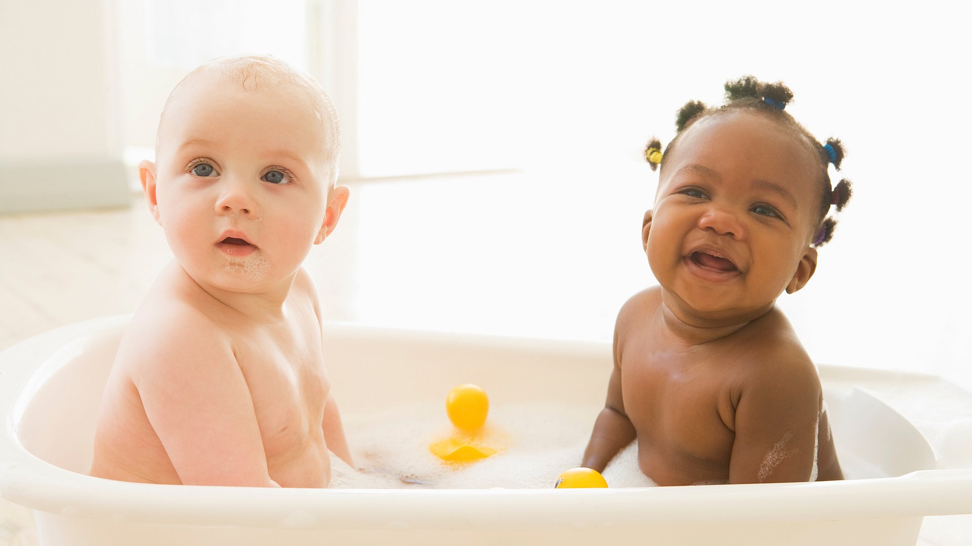 Zwei Babys sitzen zusammen in der Badewanne