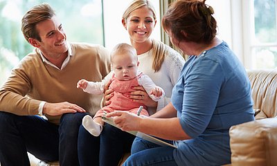 Beraterin_spricht_mit_einer_Familie_bestehend_aus_Vater_Mutter_und_Baby