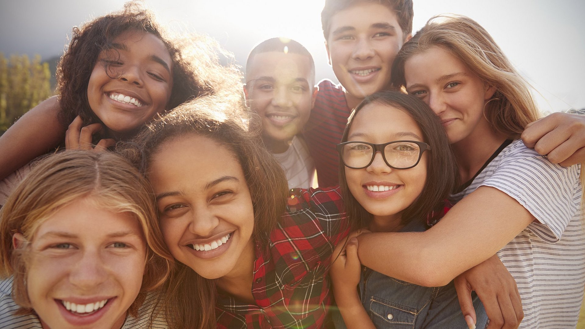 Teenager lachen in die Kamera und halten sich im Arm