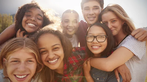 Teenager lachen in die Kamera und halten sich im Arm