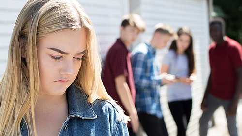 Schüler reden hinter dem Rücken einer anderen Schülerin über diese