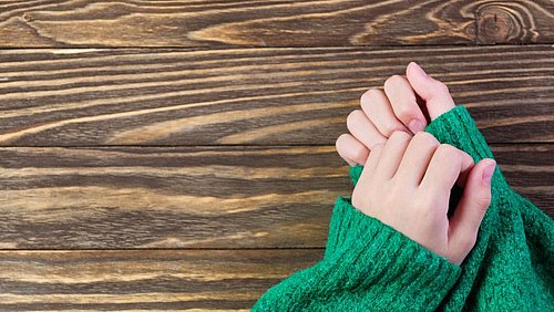 Zwei Arme mit weit heruntergezogenen Pulloverärmeln