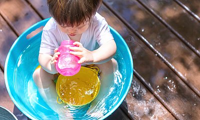 Baby sitzt in einem Becken mit Wasser und spielt