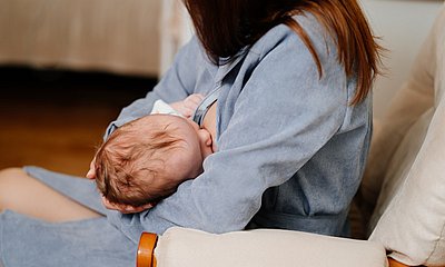 Mutter stillt Baby auf dem Sofa
