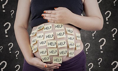 Babybauch mit Zettel beklebt auf denen Help steht