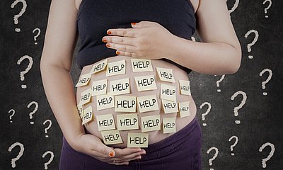 Babybauch mit Zettel beklebt auf denen Help steht